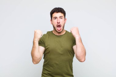 Genç adam öfkeli bir ifadeyle ya da yumruklarıyla başarıyı kutlarken agresif bir şekilde bağırıyor.