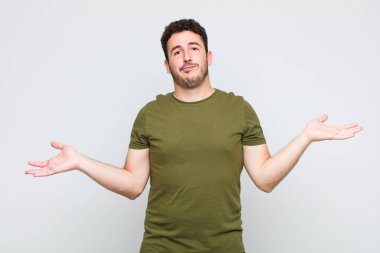 Genç adam şaşkın ve şaşkın hissediyor, doğru cevap veya karardan emin değil, bir seçim yapmaya çalışıyor.