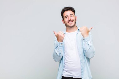 Genç adam neşeyle gülümsüyor ve mutlu görünüyor, kaygısız ve pozitif hissediyor.