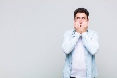 Genç adam endişeli, gergin, stresli ve korkmuş görünüyor. Tırnaklarını yiyor ve yanal fotokopi alanı arıyor.