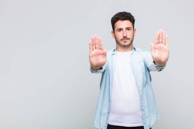 Genç adam ciddi görünüyor, mutsuz, kızgın ve hoşnutsuz giriş yasaklandı ya da her iki avuçta da dur diyor.