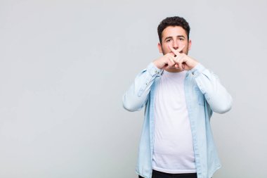 Genç adam ciddi ve hoşnutsuz görünüyor. İki parmağının önde olması reddedilerek sessizlik istiyor.