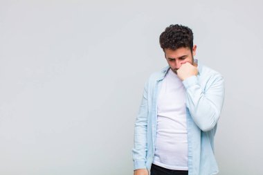 Genç adam ciddi, düşünceli ve endişeli, elleri çenesine bastırılmış, yan bakıyor