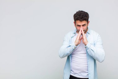 Genç adam endişeli, umutlu ve dindar, avuçlarına bastırılmış, af dileyen, sadakatle dua eden