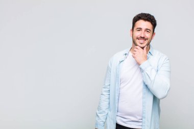 Genç adam gülümsüyor, hayattan zevk alıyor, mutlu, arkadaş canlısı, tatmin olmuş ve tasasız.