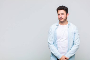 Genç adam üzgün, üzgün ya da kızgın ve olumsuz bir tavırla, anlaşmazlık içinde somurtuyor.