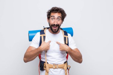 Genç adam mutlu, şaşkın ve gururlu, heyecanlı, şaşkın bakışlarla kendini işaret ediyor.