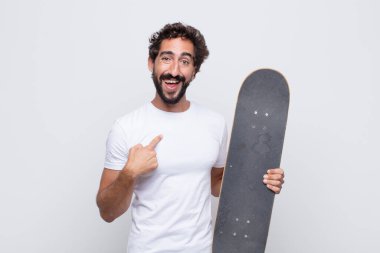 Genç adam mutlu, gururlu ve şaşırmış görünüyor, neşeli bir şekilde kendini gösteriyor, kendinden emin ve yüce hissediyor.