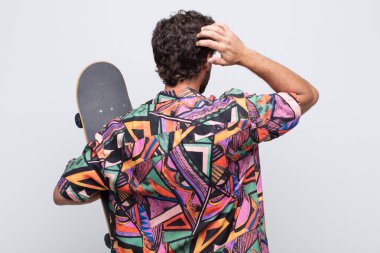 Genç adam bilgisiz ve kafası karışık, bir çözüm düşünüyor, eli kalçasında, diğeri kafasında, dikiz aynasından.