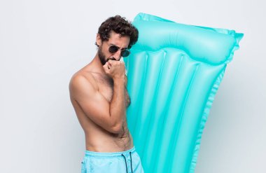 Genç adam ciddi, düşünceli ve endişeli, elleri çenesine bastırılmış, yan bakıyor