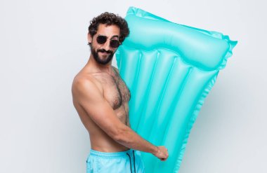 Genç adam gururlu, kendinden emin, havalı, küstah ve küstah görünüyor, gülümsüyor, başarılı hissediyor.