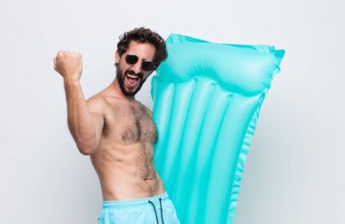 Genç adam muzaffer bir şekilde bağırıyor, heyecanlı, mutlu ve şaşırmış görünüyor.