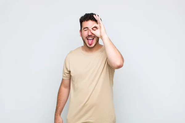 Jovem Sorrindo Feliz Com Cara Engraçada Brincando Olhando Através Espião — Fotografia de Stock