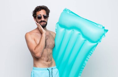 Yanak tutan ve acı çeken diş ağrısı çeken genç adam hasta, sefil ve mutsuz hisseden, dişçi arayan.