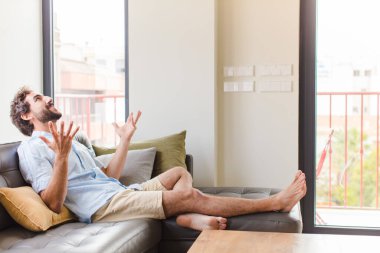 Genç adam mutlu, şaşkın, şanslı ve şaşırmış hissediyor, zaferi kutluyor, iki eli havada.