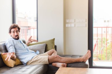 young man feeling clueless and confused, having no idea, absolutely puzzled with a dumb or foolish look