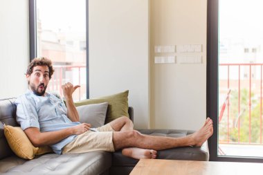 Genç adam inançsızlıktan şaşkın şaşkın bakıyor, yan taraftaki objeyi işaret ediyor ve diyor ki: