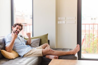 Genç adam muzaffer bir şekilde bağırıyor, gülüyor, mutlu ve heyecanlı hissediyor.