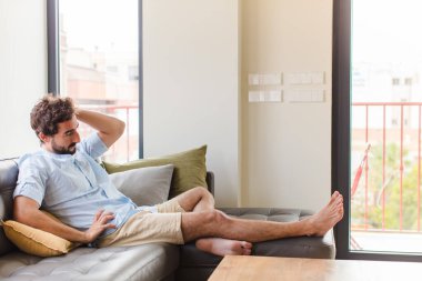 Genç adam neşeli ve sıradan bir şekilde gülümsüyor, olumlu, mutlu ve kendinden emin bir bakışla göğüs göğüse geliyor.