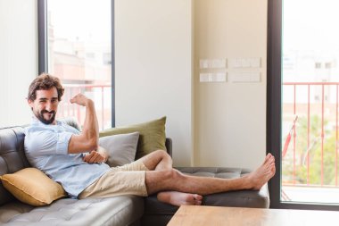 Genç adam kendini mutlu, tatmin olmuş ve güçlü hissediyor, kaslı ve formda, spor salonundan sonra güçlü görünüyor.