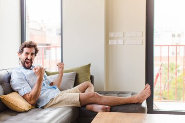 Genç adam öfkeli bir ifadeyle ya da yumruklarıyla başarıyı kutlarken agresif bir şekilde bağırıyor.