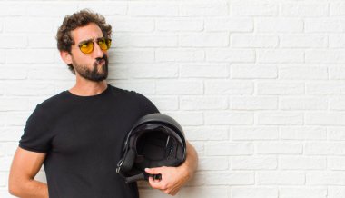 Genç adam şaşkın ve şaşkın görünüyor, merak ediyor veya bir sorunu çözmeye çalışıyor ya da düşünüyor.