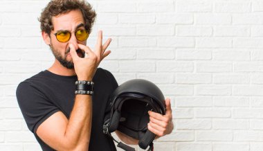 Delikanlı iğreniyor, pis ve nahoş bir koku duymamak için burnunu tutuyor.