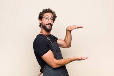 Genç adam mutlu bir şekilde gülümsüyor arkadaş canlısı, kendinden emin, pozitif bakışlı, bir nesne ya da konsept sunuyor ve gösteriyor