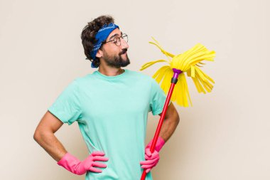 Genç adam mutlu, neşeli ve kendinden emin görünüyor, gururla gülümsüyor ve iki elini de kalçasında istiyor.