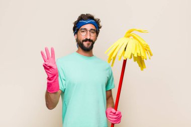 Genç adam gülümsüyor ve arkadaş canlısı görünüyor, üç ya da üç numarayı gösteriyor, eli önde, geriye doğru sayıyor.