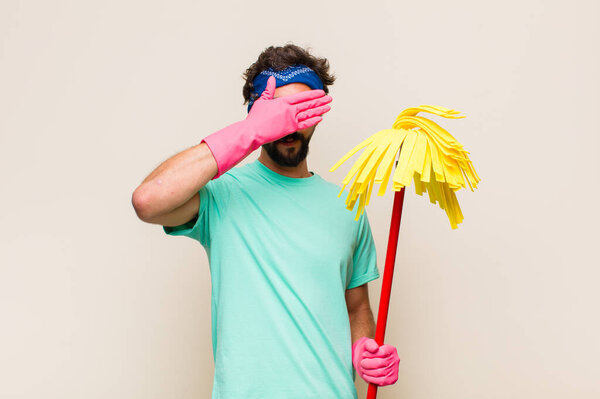 Молодой человек закрывает глаза одной рукой, испытывая страх или тревогу, удивляясь или слепо ожидая сюрприза.