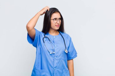 Güzel kadın şaşkın ve kafası karışmış hissediyor, başını kaşıyor ve yan tarafa bakıyor.