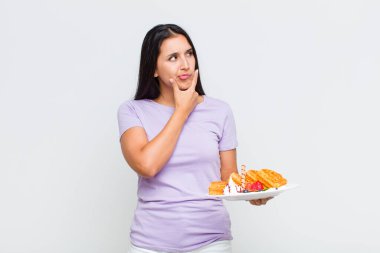 Güzel bir kadın düşünüyor, kuşkulu ve şaşkın hissediyor, farklı seçeneklerle, hangi kararı vereceğini merak ediyor.