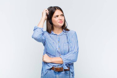 Güzel kadın şaşkın ve kafası karışmış hissediyor, başını kaşıyor ve yan tarafa bakıyor.