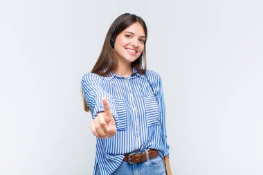 Güzel bir kadın gururla gülümsüyor ve gururla bir numaralı pozunu veriyor, kendini lider gibi hissediyor.