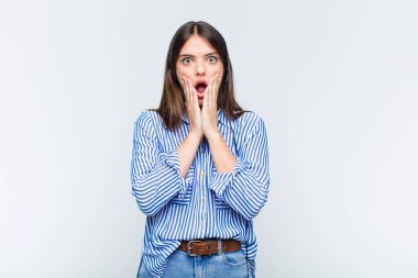 Güzel kadın şok olmuş ve korkmuş hissediyor, ağzı açık ve elleri yanaklarında korkmuş görünüyor.
