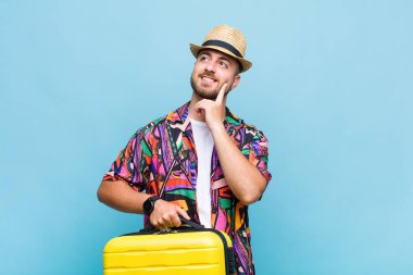 Genç adam mutlu bir şekilde gülümsüyor ve hayal kuruyor ya da şüphe ediyor.