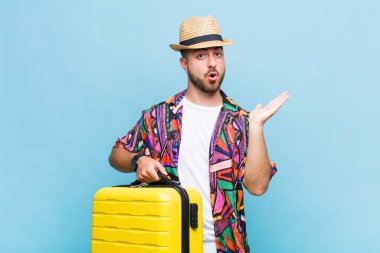 Genç adam şaşırmış ve şok olmuş görünüyor, çenesi düşmüş bir nesneyi elinde açık bir elle tutuyor.