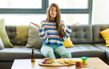 Güzel bir kadın şaşkın ve şaşkın hissediyor, şüpheci, farklı seçenekleri tartıyor veya komik bir ifadeyle seçiyor.