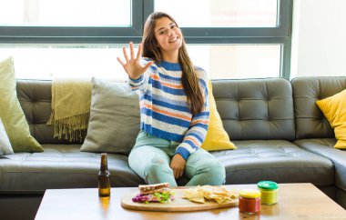 Güzel bir kadın gülümsüyor ve arkadaş canlısı görünüyor, 5 ya da 5 numarayı gösteriyor, elleri önde, geriye doğru sayıyor.