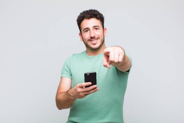 Genç adam kameraya tatmin olmuş, kendinden emin, dostane bir gülümsemeyle bakıyor ve seni seçiyor.