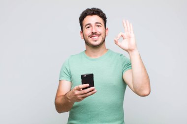 Genç adam mutlu, rahat ve tatmin olmuş hissediyor. Onayını iyi bir hareketle gösteriyor. Gülümsüyor.