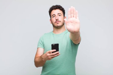 Genç adam ciddi, sert, hoşnutsuz ve kızgın görünüyor. Avuç içinin açık olması jesti durduruyor.