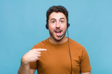 Genç adam mutlu, şaşkın ve gururlu, heyecanlı, şaşkın bakışlarla kendini işaret ediyor.