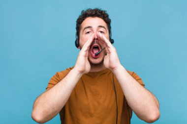 Genç adam mutlu, heyecanlı ve pozitif hissediyor. Elleri ağızda, bağırıyor.