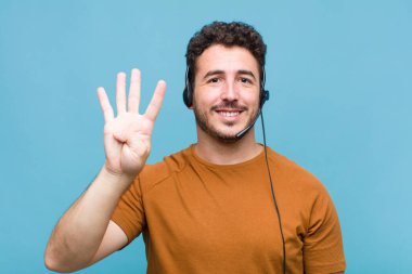 Genç adam gülümsüyor ve arkadaş canlısı görünüyor, dört ya da dört numarayı gösteriyor, eli önde, geriye doğru sayıyor.