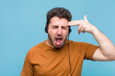 Genç adam mutsuz ve stresli görünüyor, intihar jesti elle silah işareti yapıyor, kafasını işaret ediyor.