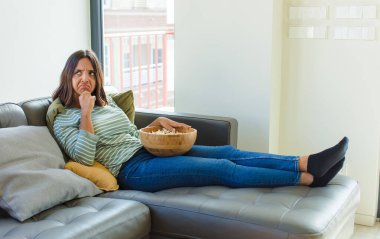 Güzel bir kadın düşünüyor, kuşkulu ve şaşkın hissediyor, farklı seçeneklerle, hangi kararı vereceğini merak ediyor.