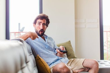 Sakallı adam şok olmuş ve ağzı açık, kendini işaret ederek şaşırmış görünüyor.