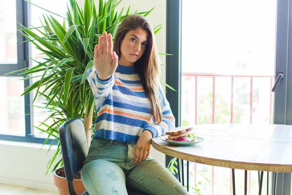 pretty woman looking serious, stern, displeased and angry showing open palm making stop gesture